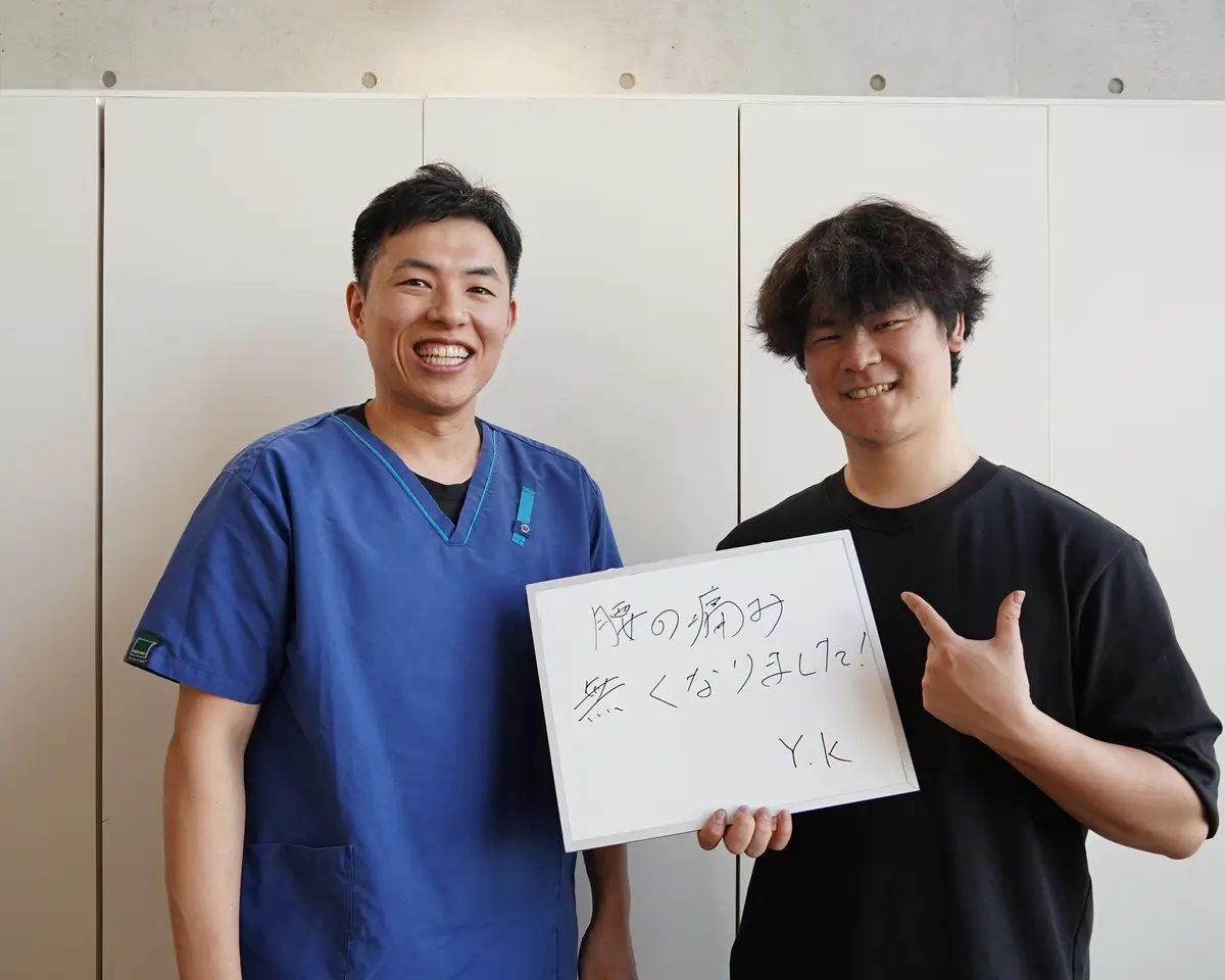 院長と来院された方が「腰の痛み無くなりました!」と書いた手書きボードを持つ写真